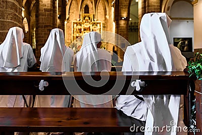 Valencia, Spain - September 25, 2019: Group of Christian nuns with white robes praying in a church Editorial Stock Photo
