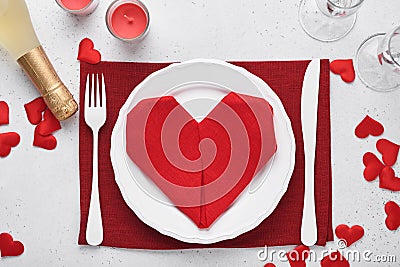 Valentinas day table setting white color with white silverware, red napkin folded as heart, candles, champagne, glasses on white Stock Photo