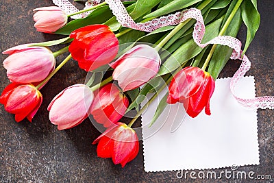 Valentine background or greeting card. Congratulatory sheet of paper with red and Ð¿Ð¸Ð½Ðº tulips on a dark stone background. Stock Photo