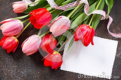 Valentine background or greeting card. Congratulatory sheet of paper with red and Ð¿Ð¸Ð½Ðº tulips on a dark stone background. Stock Photo