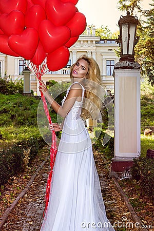 Valentine Beautiful girl with red balloons laugh, in the park. Beautiful happy young woman. Birthday party and bride at the Stock Photo