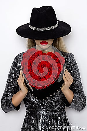 Valentine Beauty girl with red heart roses. Portrait of a young female model with gift and hat, isolated on background. Stock Photo