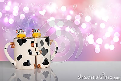 Valentine day concept. Sweet cows hug each other as a form of two mugs on a bright table in front of a love hearts Stock Photo