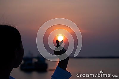 Valentine day and Marry Concept. Female model is showing mini heart hand symbol on the beach sunset or sunrise background Stock Photo