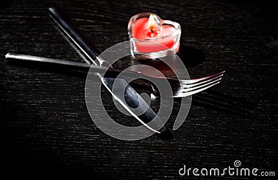 Valentine day table setting with knife, fork, red burning heart shaped candle Stock Photo