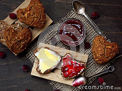 Valentine`s Day breakfast. Composition of wholegrain muffins in the form of heart with butter, cheese and jam. Stock Photo