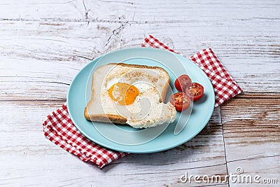 Valentine's Day breakfast with egg with tomatoes, heart shaped and toast bread on wooden table Stock Photo