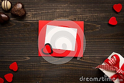 Valentine`s Day card on the wooden background. Gift box, red hearts and chocolate on the wooden desk. Stock Photo