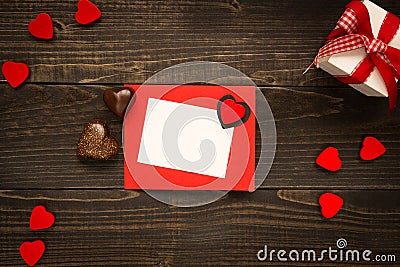 Valentine`s Day card on the wooden background. Gift box, red hearts and chocolate on the wooden desk. Stock Photo