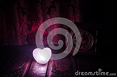 Valentine's Day composition with sweet burning multicolored heart on dark background and old vintage clock, time and love Stock Photo