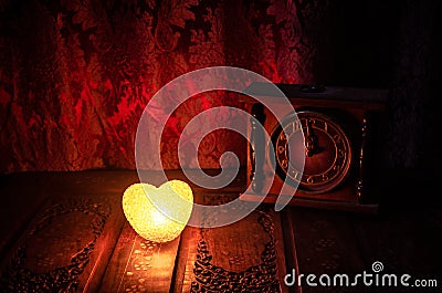 Valentine's Day composition with sweet burning multicolored heart on dark background and old vintage clock, time and love concept, Stock Photo