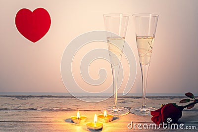 ValentineÂ´s day composition with two glasses of champagne, heart, rose and candles on white wooden background. Stock Photo
