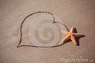 Valentine's day concept at beach. big orange starfish and drawn heart on sand texture. Stock Photo