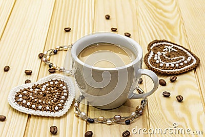 Valentine`s Day concept. Cup of coffee, knitted heart, string of pearl beads. Romantic breakfast and gift on wooden boards Stock Photo