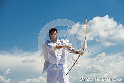 Valentine's Day concept. Funny angel cupid aiming with bow and arrow on a sky background in heaven. Stock Photo