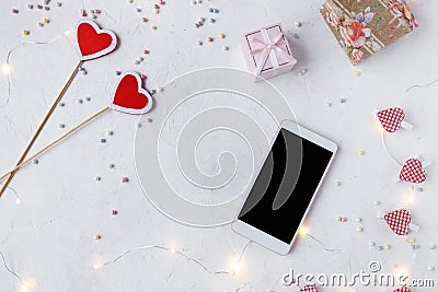 Valentine`s day concept. Hearts, confetti, smartphone, decor, lights on a light background Stock Photo