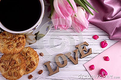 Valentine`s day elegant still life with tulip flowers cup of coffe marshmallow lettering love sign on white wooden background Stock Photo