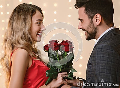 Valentine`s Day Flowers. Loving Man Giving Roses To His Happy Girlfriend Stock Photo
