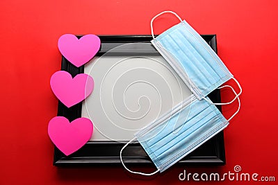 Valentine`s Day gifts in pandemic by covid-19, picture holder and flowers with protection mask for clinical use and pink hearts Stock Photo