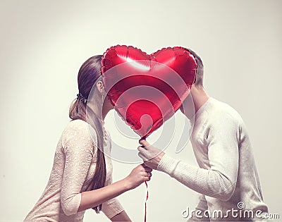 Valentine`s day. Happy joyful couple holding heart shaped air balloon and kissing Stock Photo