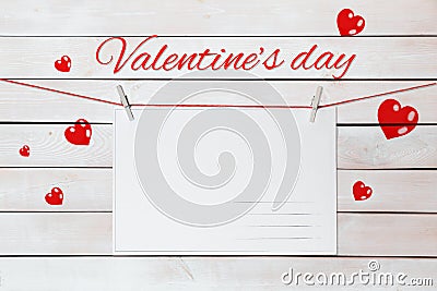 Valentine`s day lettering and postcards on red threads surrounded by hearts on wooden white background Stock Photo
