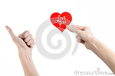 Valentine's Day and love theme: hand holds a greeting card in the form of a red heart with the words Love you isolated Stock Photo