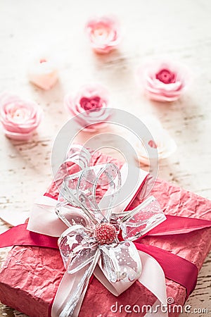 Valentina`s day and mothers day concept, red gift box with bow and roses on light wooden background Stock Photo