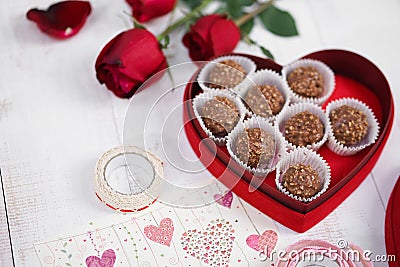 Valentine`s day. Nutty chocolate in a red heart box and red roses for Valentine`s or anniversary present. Soft focus on the nutt Stock Photo