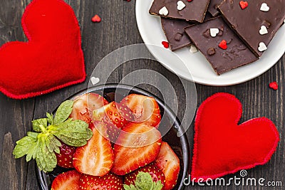 Valentine`s Day romantic concept. Chocolate, fresh ripe strawberry, red felt hearts. Sweet dessert for lovers. Black wooden Stock Photo
