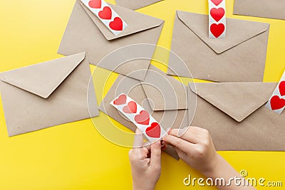 Valentine& x27;s day. Hands glue red hearts on envelopes, yellow background. The holiday is February 14. Love letters Stock Photo