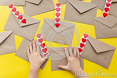 Valentine& x27;s day. Hands glue red hearts on envelopes, yellow background. The holiday is February 14. Love letters Stock Photo