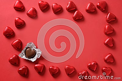 Valentine's day romantic chocolate sweets as heart in red foil as frame on red. Stock Photo