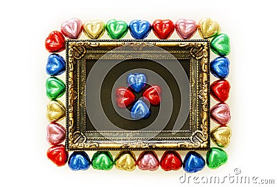 Valentines Day background with colorful chocolates heart shape and gold frame from top view. Stock Photo