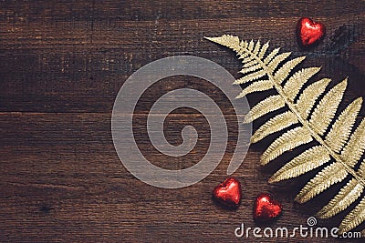 Valentines Day background, mockup with red heart shape chocolate candies and golden leaves on wooden background. Valentine Day, Stock Photo