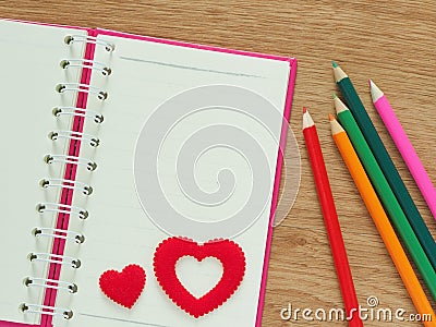 Valentines day background with red hearts, book for diary and color pencils on wood floor. Love and Valentine concept Stock Photo