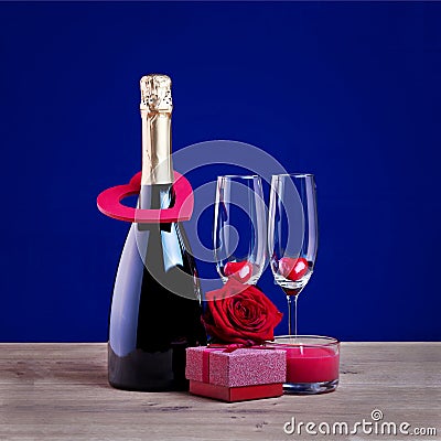 Valentines day concept with champagne glasses candle and hearts against blue background. Stock Photo