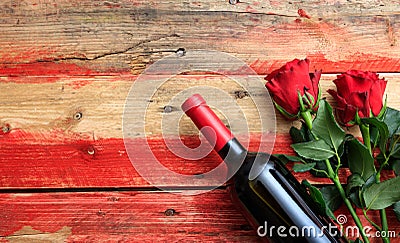 Valentines day. Red wine bottle and red roses on wooden background Stock Photo