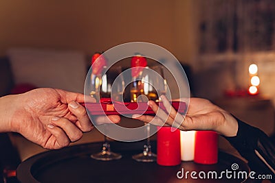 Valentines Day couple exchanging presents having wine drinks during romantic dinner celebrating at home. Red gift box Stock Photo