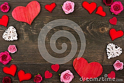 Valentines Day frame of wooden hearts and paper flowers against dark wood Stock Photo