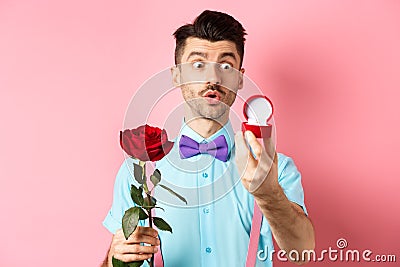 Valentines day. Romantic funny guy going to make wedding proposal, asking to marry him, holding red rose and looking at Stock Photo