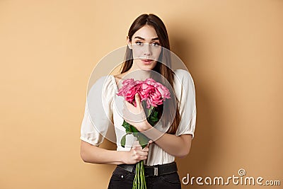 Valentines day. Surprised tender girl thanking for flowers and smiling, holding red roses and smiling grateful, standing Stock Photo