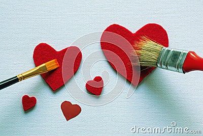 Valentines. Drawing of two red hearts of different size with two paintbrushes on canvas. Copy space Stock Photo