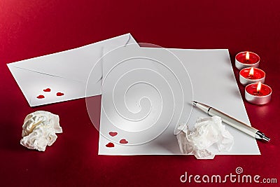 Valentines love letter writing setup, with envelope, paper, red background, candles and fire, flame and tissues. Stock Photo