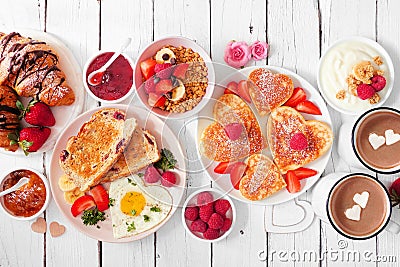 Valentines or Mothers Day breakfast table scene on a white wood background with heart shaped pancakes, eggs and love themed food Stock Photo