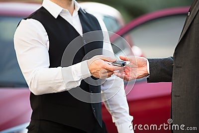 Valet Giving Car Key To Businessperson Stock Photo