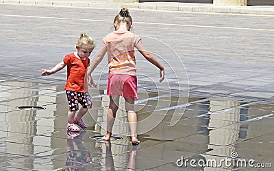 It`s very hot and two children playing in the fountain in the square Editorial Stock Photo