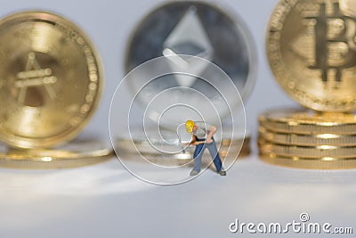 valueable crypto coins bitcoin ether and ada in a row with a single worker on gray background detail Editorial Stock Photo