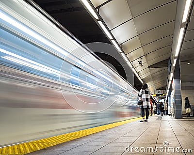 Vancouver City Center station at evening rush hour with trains rushing by and commuters waiting. Stock Photo