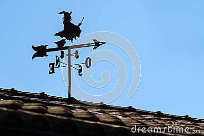 Vane on roof of house outdoor with witch and arrow pointing the direction of the wind Stock Photo