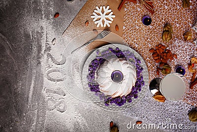 A vanilla cake with flowers on a plate. A New Year composition on a gray background. The inscription 2018 on a desk. Stock Photo